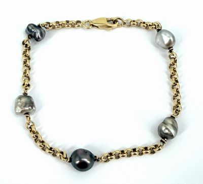 un gros plan sur un bracelet à chaîne en or orné de perles noires