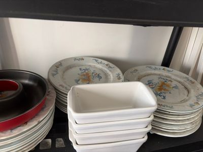 many plates and pans on a shelf in the kitchen