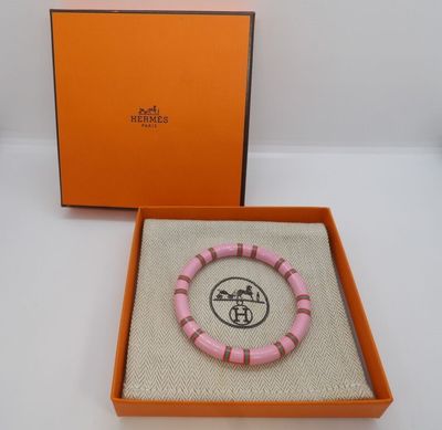 an orange box with a pink bracelet inside of it on a white surface
