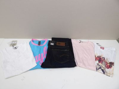 trois paires de t-shirts et un jean posés sur une table