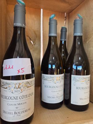 plusieurs bouteilles de vin sont alignées sur une étagère en bois