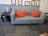 a grey couch with orange pillows on it in a living room