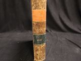 an old book sitting on top of a black cloth covered table