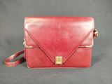 a red leather handbag with a gold clasp on the front