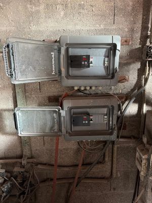 trois compteurs électriques fixés au mur d'un immeuble, auxquels sont raccordés des fils