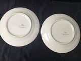 two white plates sitting on top of a black cloth covered table
