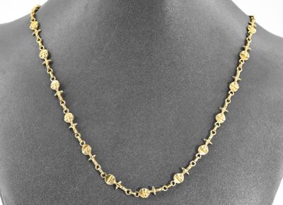 a gold necklace with flowers and leaves on a mannequin mannequin