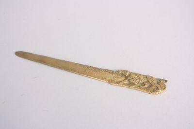 une cuillère en or ornée d'un motif sur un fond blanc
