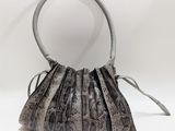 sac à main en peau de serpent sur fond blanc, avec un miroir en arrière-plan