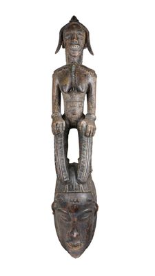 une vieille statue en bois représentant un homme assis sur une tête