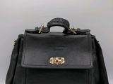a black leather handbag with gold hardware on the handle