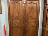 une armoire en bois dans une pièce où est accrochée une horloge au mur