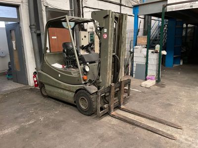 un chariot élévateur vert garé dans un garage à côté d'un immeuble