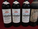 four bottles of wine are lined up on a red surface
