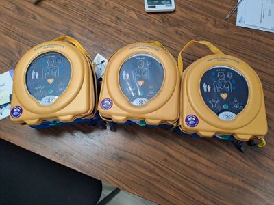 trois moniteurs cardiaques posés sur une table à côté d'un téléphone portable