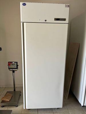 a white refrigerator in the middle of a room with a scale