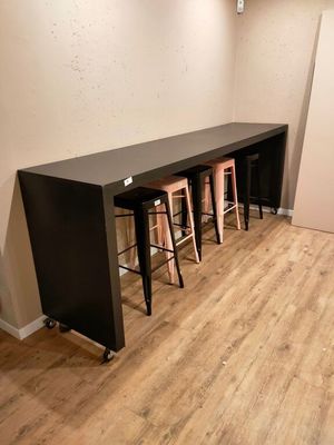 une longue table avec quatre tabourets dans un coin de la pièce