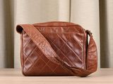 brown leather cross body bag on a table with curtains in the background