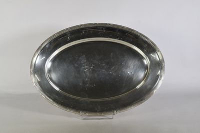 une assiette ovale en argent posée sur un socle, sur fond blanc