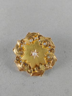 a close up of a gold broochle with a diamond in the center