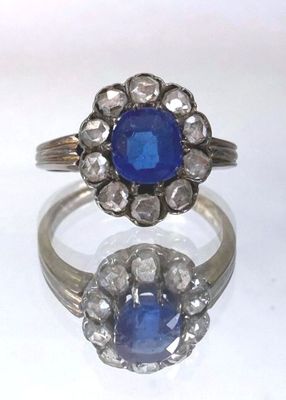 an image of a ring with a blue stone surrounded by diamonds