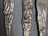 three silver spoons and a fork with a statue on them