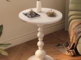 une table blanche sur laquelle se trouve une plante, dans un coin de la pièce
