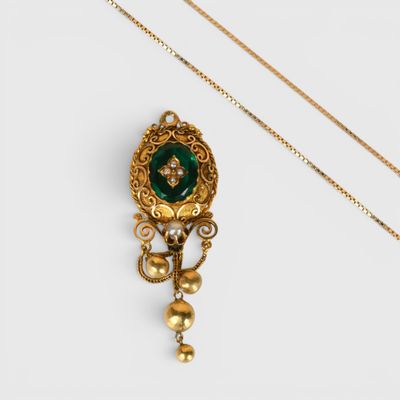 un gros plan d'un collier en or orné d'une pierre verte