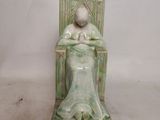 a figurine of a woman sitting in a chair