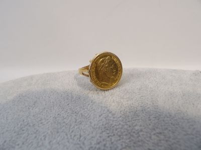 Gros plan sur une bague en or ornée d'une pièce de monnaie