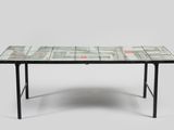La table est fabriquée à partir de pages de journaux et possède un piètement en métal noir.