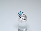 an image of a diamond and blue topaz ring on a clear glass