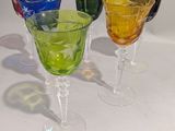 quatre verres à vin de couleurs différentes posés sur une table blanche