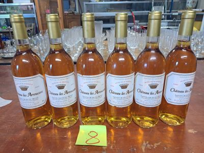 Six bouteilles de vin sont alignées sur une table, accompagnées d'une étiquette de prix