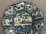 a blue and white plate with a picture of people on it