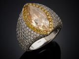 a close up of a ring with a pear shaped stone surrounded by yellow and white diamonds
