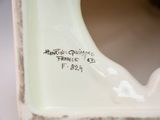 a close up of a white vase with a bird on it
