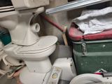 a white toilet sitting next to a green and red trash can