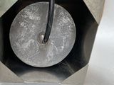 a metal object with a black handle on a table