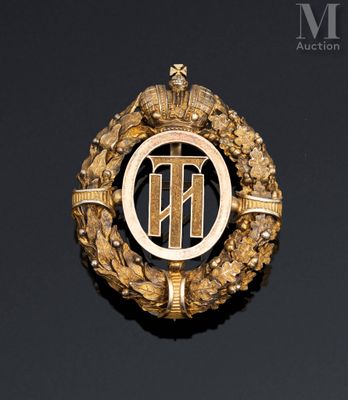 an image of a gold broochle with the letter t on it
