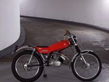 a red motorcycle parked in a parking garage next to a white wall