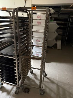 Plusieurs plateaux de nourriture sont empilés sur un chariot dans une cuisine