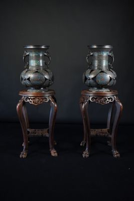 une paire de vases chinois anciens posés sur des socles, sur fond noir