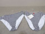 pair of black and white striped panties on a bed with a tag