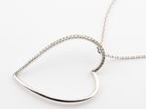 un pendentif en forme de cœur en argent avec une chaîne, sur fond blanc