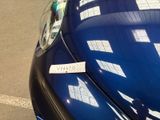 a sticker on the hood of a car that is parked on the side of the road