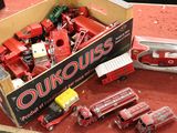 une boîte remplie de camions rouges en plastique posée sur un tapis rouge