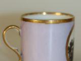 a small cup with a gold rim on a white table