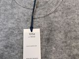 a close up of a gray sweater with a tag on it