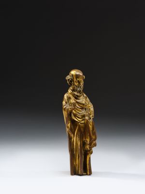 a gold figurine of a man with a hat and robe